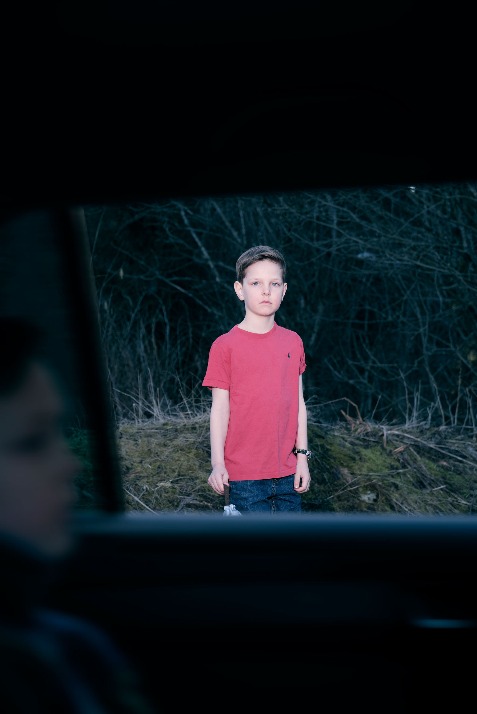 gutt i rød t-skjorte sett gjennom vinduet til bil i fart